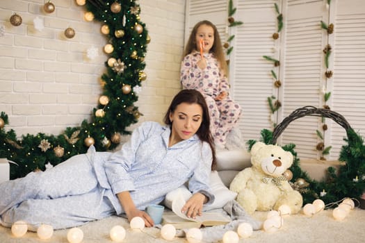 happy mother with her little child daughter playing near the Christmas tree