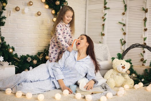 happy mother with her little child daughter playing near the Christmas tree