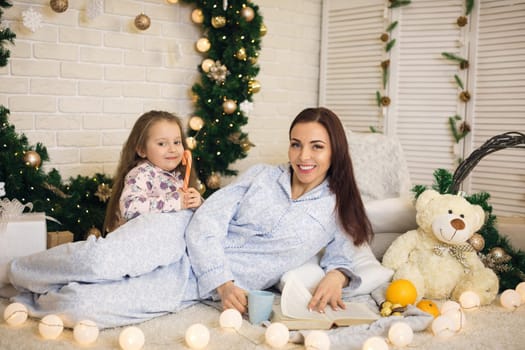 happy mother with her little child daughter playing near the Christmas tree