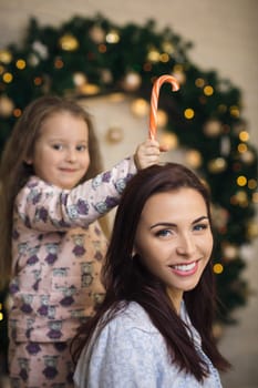 happy mother with her little child daughter playing near the Christmas tree