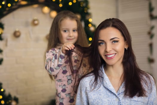 happy mother with her little child daughter playing near the Christmas tree
