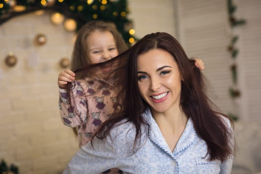 happy mother with her little child daughter playing near the Christmas tree