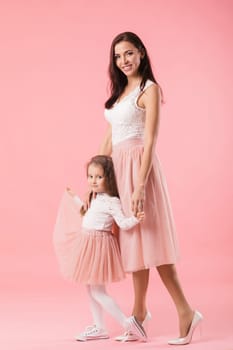 pretty, charming mother and smiling daughter on pink background, hugging, looking at camera, women's day. Mother's day