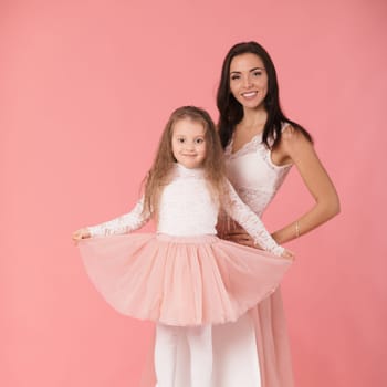 pretty, charming mother and smiling daughter on pink background, hugging, looking at camera, women's day. Mother's day