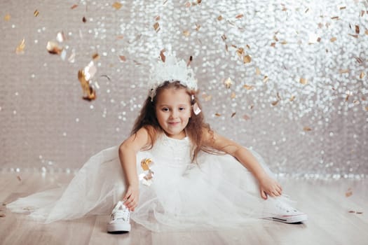 cute little child girl in princess dress on confetti background with silver bokeh. birtday party