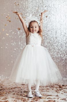cute little child girl in princess dress on confetti background with silver bokeh. birtday party