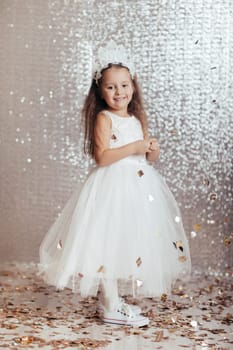 cute little child girl in princess dress on confetti background with silver bokeh. birtday party