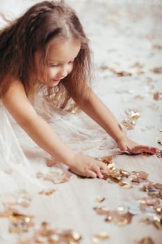 cute little child girl in princess dress on confetti background with silver bokeh. birtday party