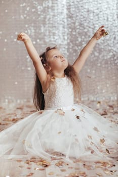 cute little child girl in princess dress on confetti background with silver bokeh. birtday party