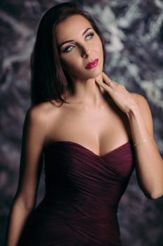Portrait of magnificent sexy woman in evening dress posing over dark background