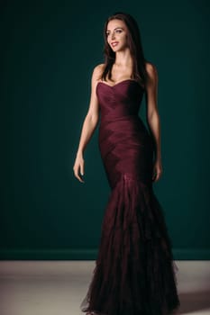 gorgeous fashion woman in evening dress posing over dark green background