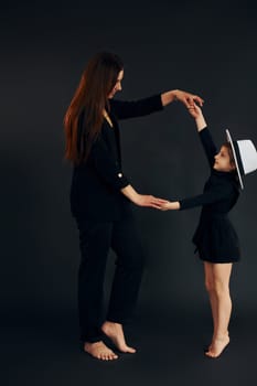 Mother and daughter is together in the studio against black background.