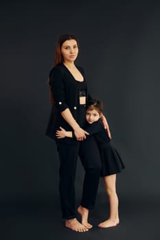 Mother and daughter is together in the studio against black background.