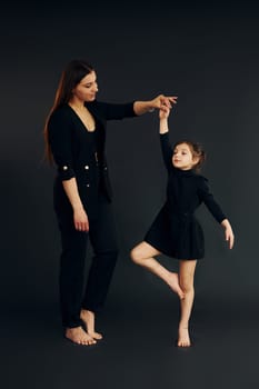 Mother and daughter is together in the studio against black background.