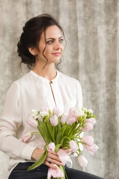 portrait of a beautiful brunette woman with a bouquet of tulips flowers