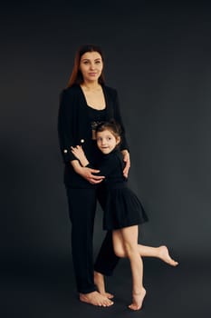 Mother and daughter is together in the studio against black background.