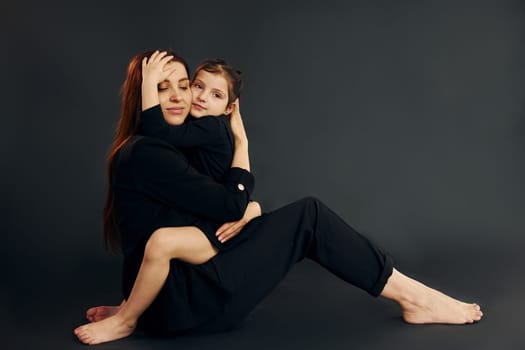 Mother and daughter is together in the studio against black background.