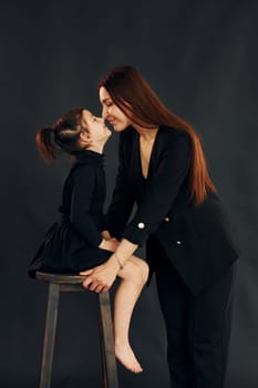 Mother and daughter is together in the studio against black background.