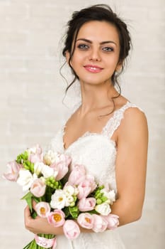 Portrait of beautiful bride with wedding bouquet of pink tulips