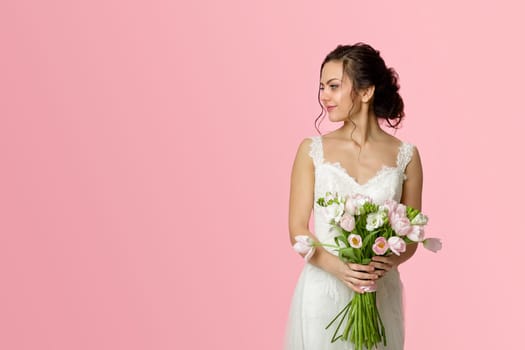 beautiful bride with wedding bouquet of pink tulips on pink background