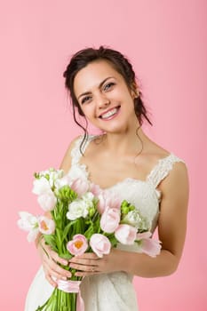 beautiful bride with wedding bouquet of pink tulips on pink background