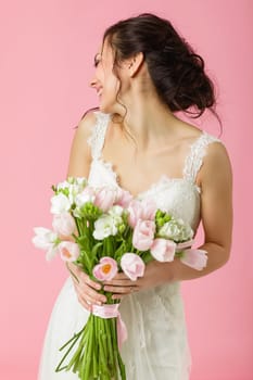 beautiful bride with wedding bouquet of pink tulips on pink background