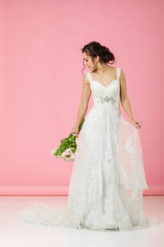 beautiful bride with wedding bouquet of pink tulips on pink background