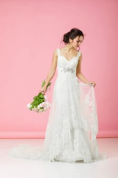 beautiful bride with wedding bouquet of pink tulips on pink background