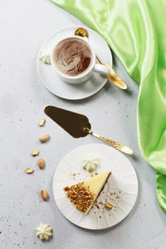 A piece of pistachio cake with a cup of coffee on a concrete background. View from above. Vertical photo.