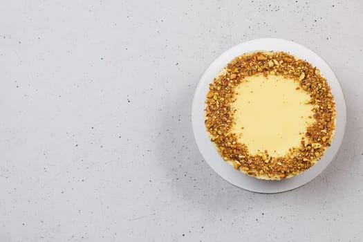 Pistachio cake on a stand on a gray background. Ingredients: pistachio sponge cake, pistachio mousse, chocolate mousse and white chocolate mousse.Copy space.