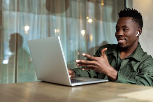 Handsome african american man using computer and smiling. Online video chat with business partners