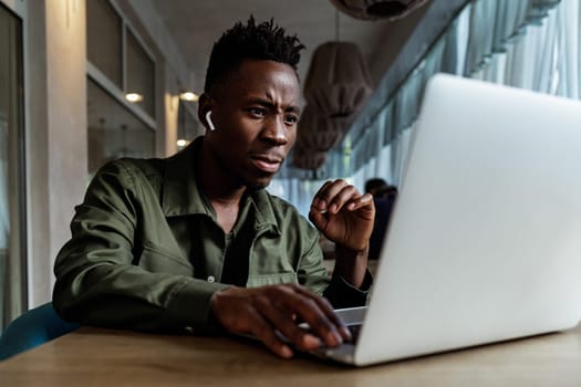 african american man using computer in cafe. young businessman working on his laptop. Empty space