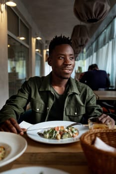 young african american man is eating in a restaurant and enjoying delicious food