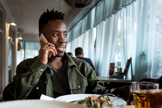 young african american man talking on smartphone in cafe. copy space