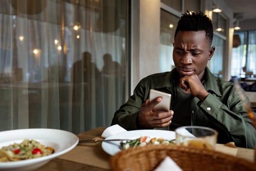 young african american man messaging online, checking social networks in cafe. copy space