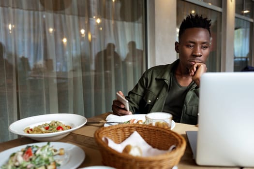 young african american man using laptop in cafe