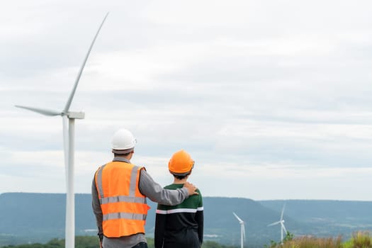 Engineer with his son on a wind farm atop a hill or mountain in the rural. Progressive ideal for the future production of renewable, sustainable energy. Energy generation from wind turbine.