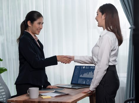 Successful job interview between Asian woman candidate and interviewer at the business office with handshake. Positive discussion of qualifications and application for the position. Enthusiastic