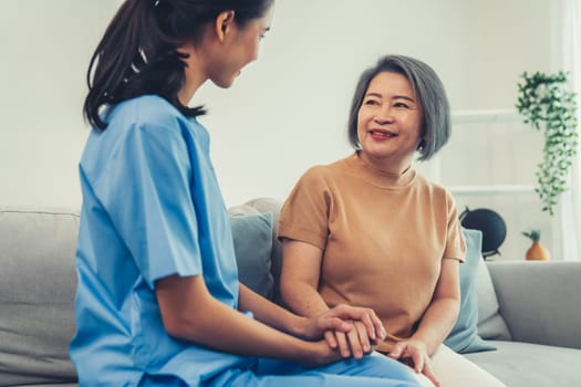 A contented senior woman visited by her personal caregiver and hold each other's hands.