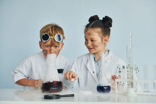 Boy works with liquid in test tubes. Children in white coats plays a scientists in lab by using equipment.