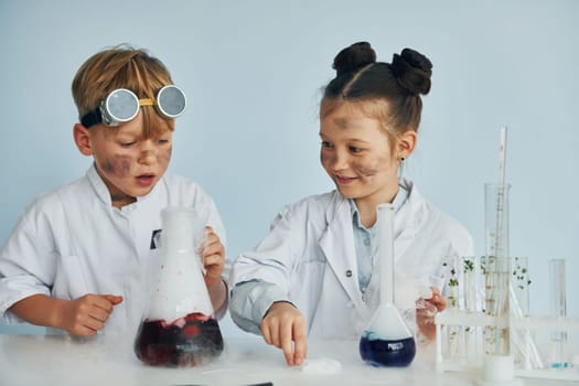 Boy works with liquid in test tubes. Children in white coats plays a scientists in lab by using equipment.