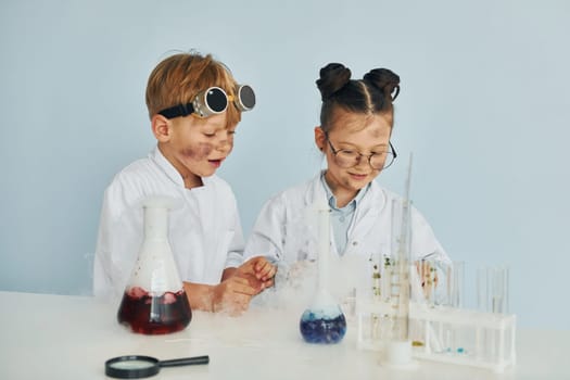 Boy works with liquid in test tubes. Children in white coats plays a scientists in lab by using equipment.