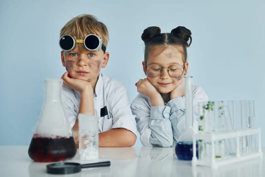 Girl with boy working together. Children in white coats plays a scientists in lab by using equipment.