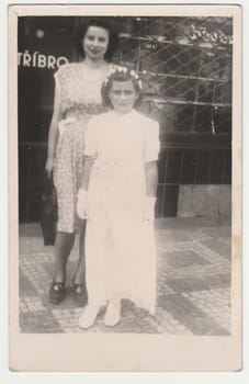 THE CZECHOSLOVAK SOCIALIST REPUBLIC - CIRCA 1950s: Vintage photo shows mother and daughter after her first communion. Retro black and white photography. Circa 1950s.