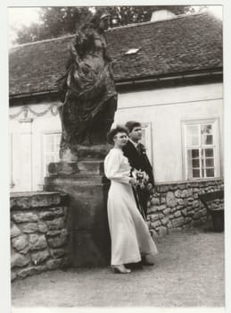 THE CZECHOSLOVAK SOCIALIST REPUBLIC - CIRCA 1980s: Vintage photo shows a newlyweds pose in front of historic statue. Retro black and white photography. Circa 1980s.