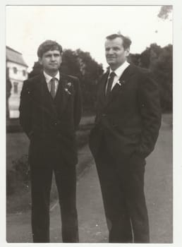 THE CZECHOSLOVAK SOCIALIST REPUBLIC - CIRCA 1970s: Vintage photo shows wedding guests - men pose outdoors. Retro black and white photography. Circa 1970s.