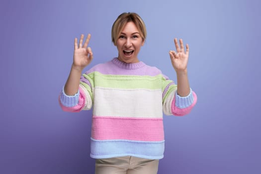 cute attentive blond young woman showing class gesture on purple background.