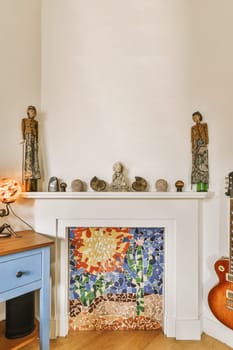 flowers on the fireplace in a room with white walls and wood flooring, including an electric guitar next to it