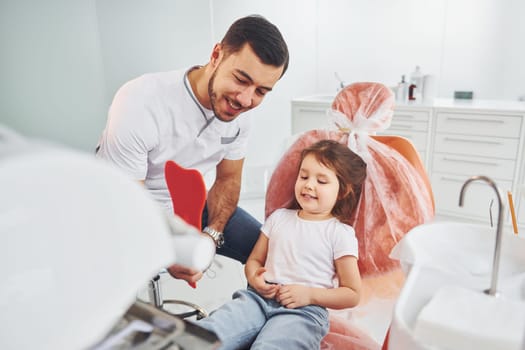 Looks into the mirror. Little girl visiting dentist in clinic. Conception of stomatology.