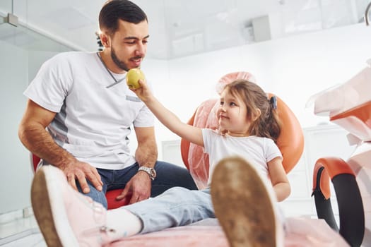 Sits on the chair. Little girl visiting dentist in clinic. Conception of stomatology.